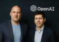 Jony Ive and Sam Altman stand side by side in front of the OpenAI logo, marking a $6.5B collaboration on a new AI hardware device.